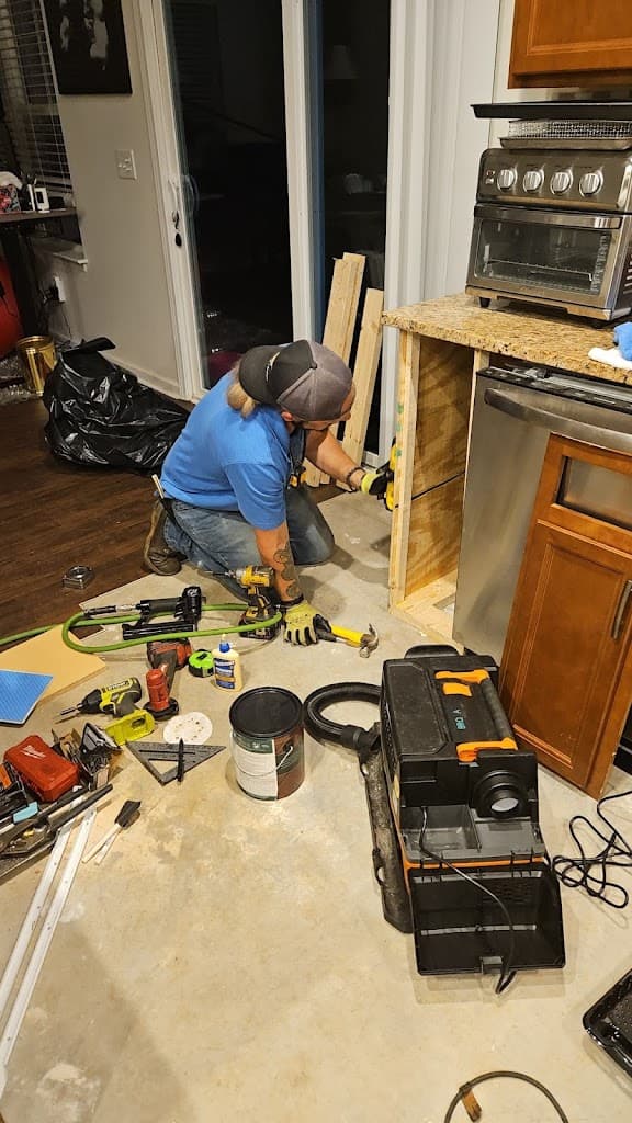 Brent installing a kitchen cabinet base, tools spread across the floor